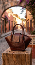 Burnt brown leather flare tote bag on rustic wooden surface in Mexican alley