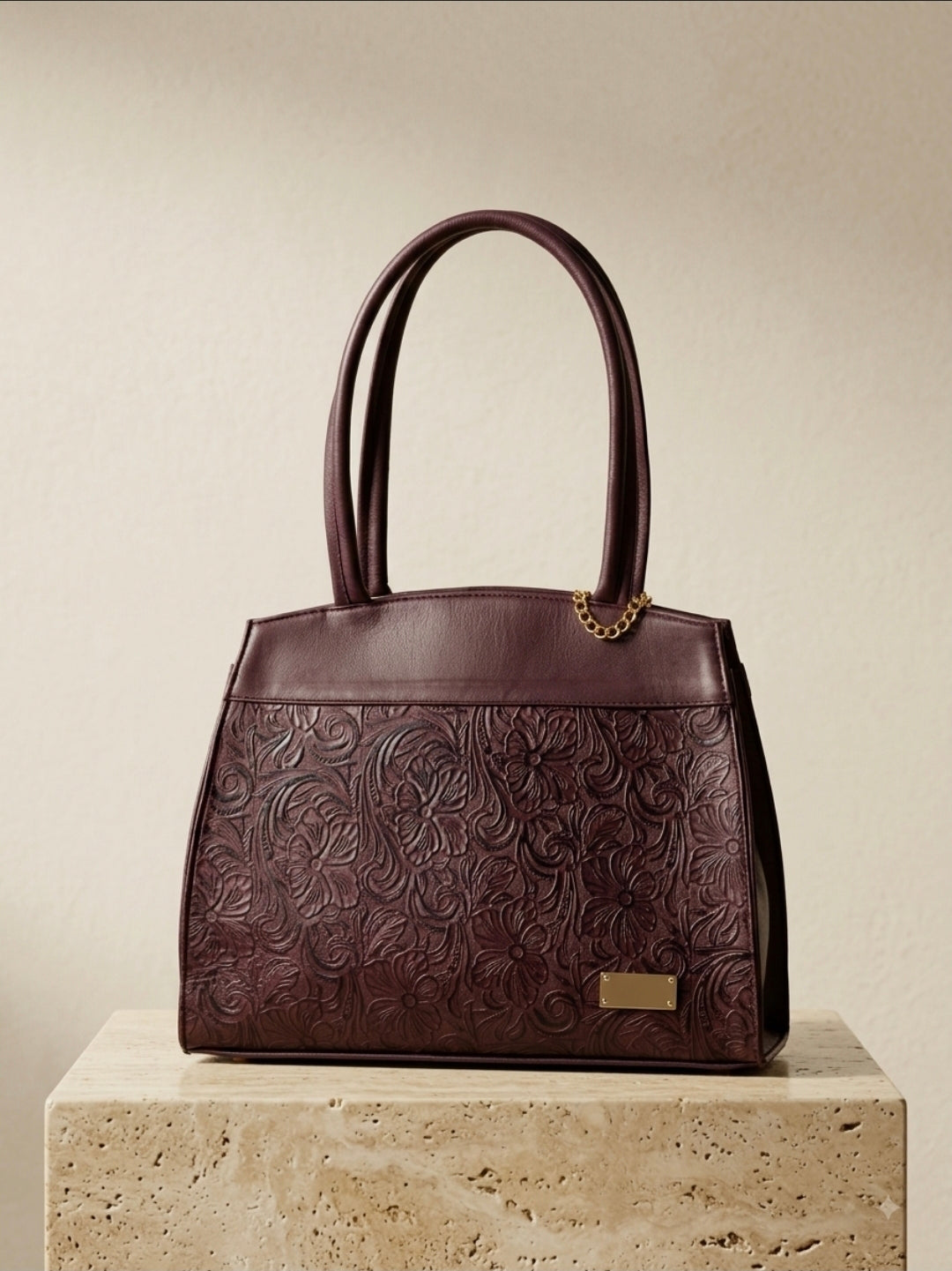 Deep burgundy hand-tooled leather handbag with shoulder strap and gold hardware, handmade in México