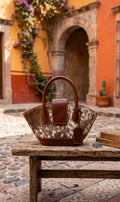 Burgundy and hide leather flare tote bag on rustic wooden table