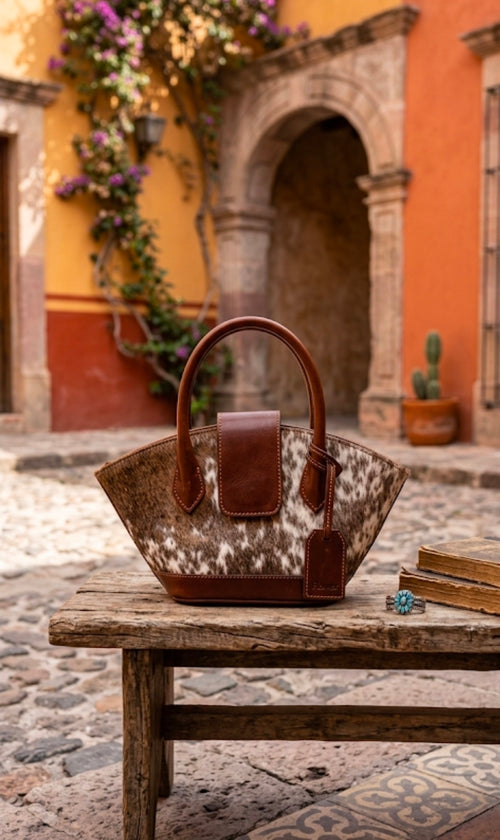 Burgundy and hide leather flare tote bag on rustic wooden table